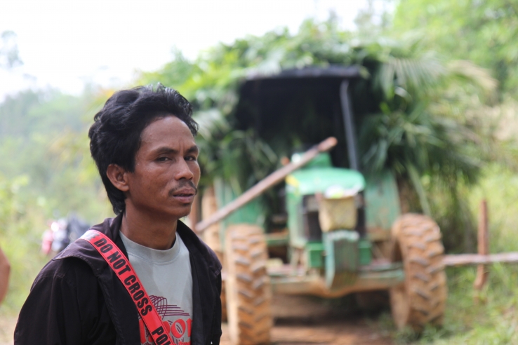 One of the village leaders stands in front of a confiscated palm oil company truck.